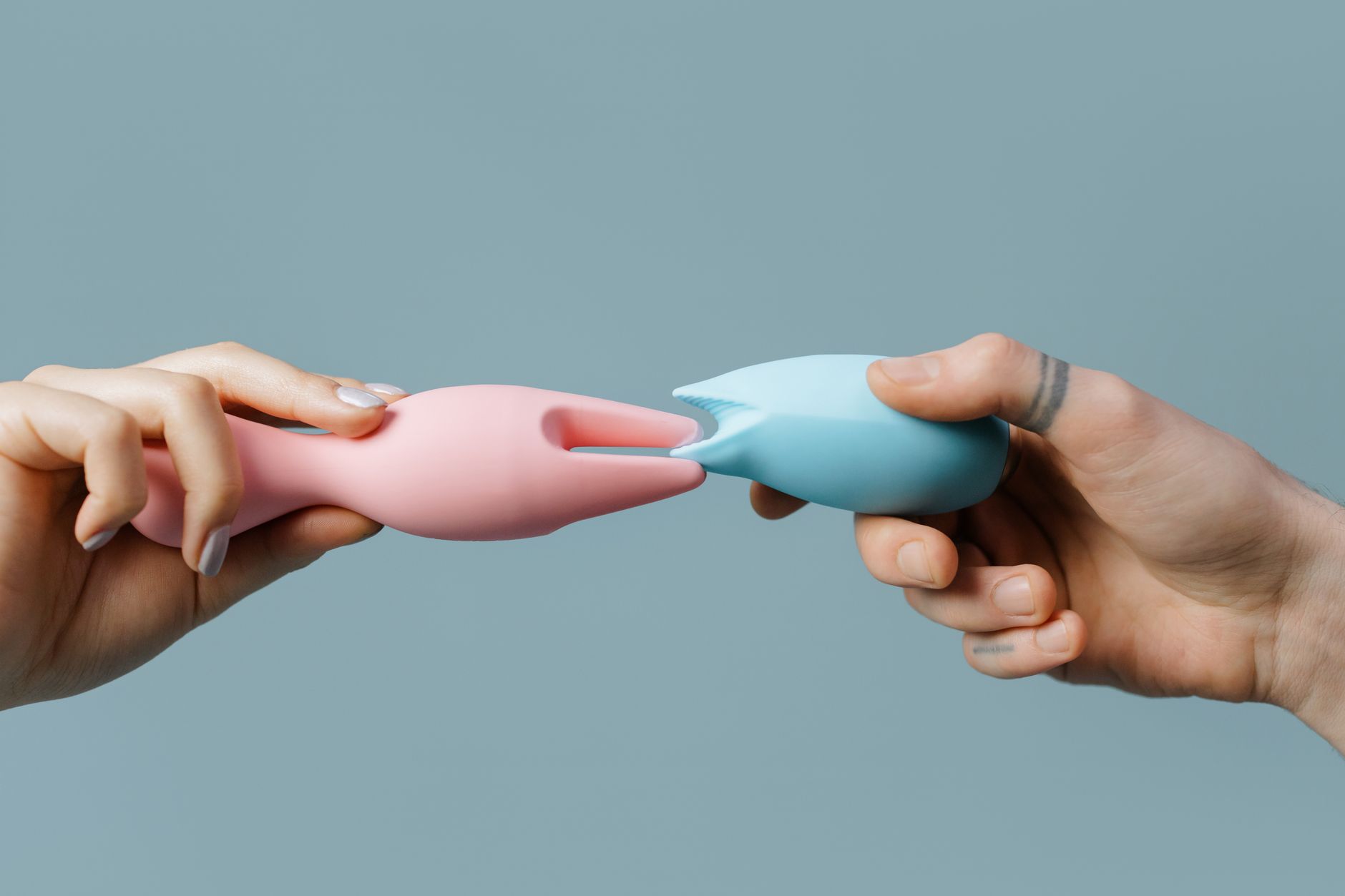 Hands holding pastel-colored silicone toys, perfect for intimate wellness