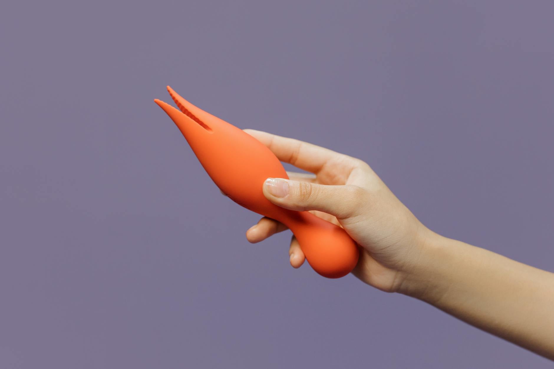Hand holding a lemon vibrator against a minimalistic purple backdrop, showcasing modern sensuality