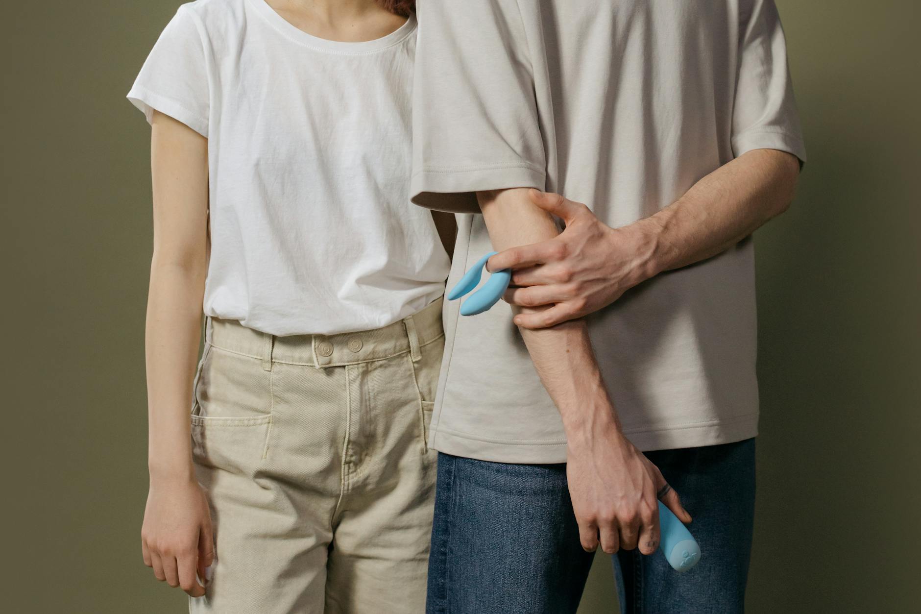 A couple holding a blue vibrator together, symbolizing modern intimacy and shared pleasure.
